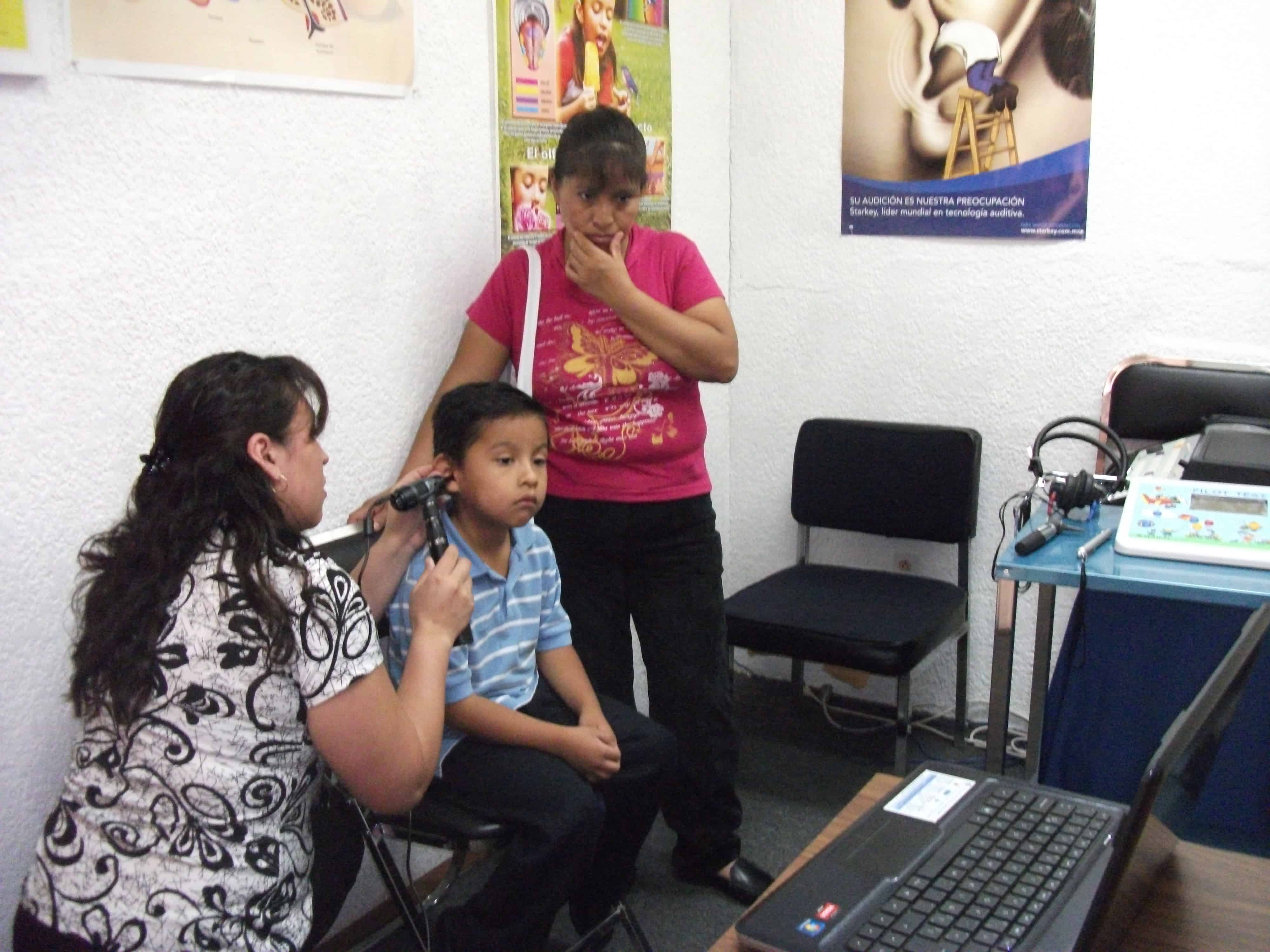 Audióloga realizando otoscopia a un niño en consulta